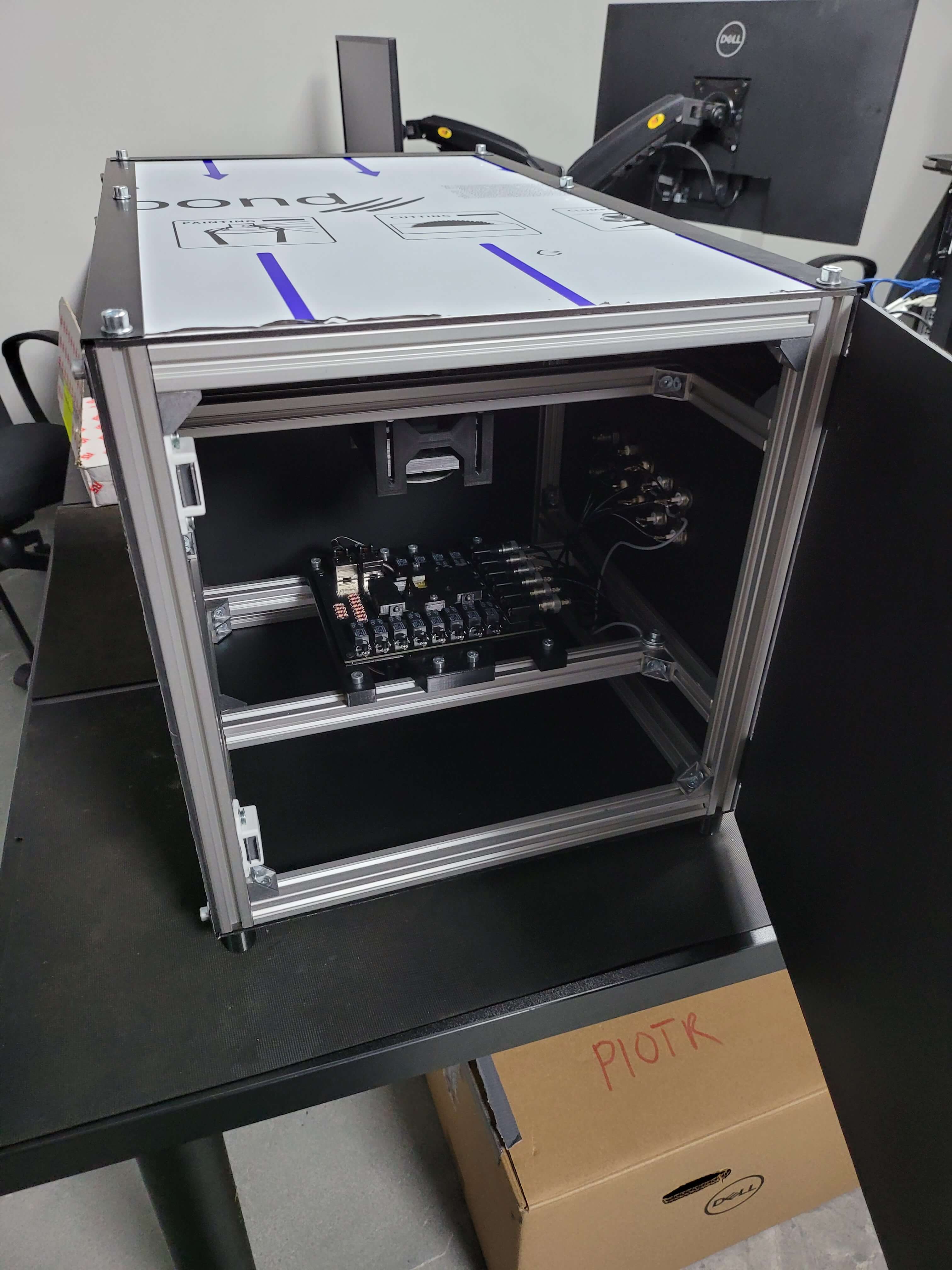 Otwarta metalowa obudowa na biurku z widoczną elektroniką